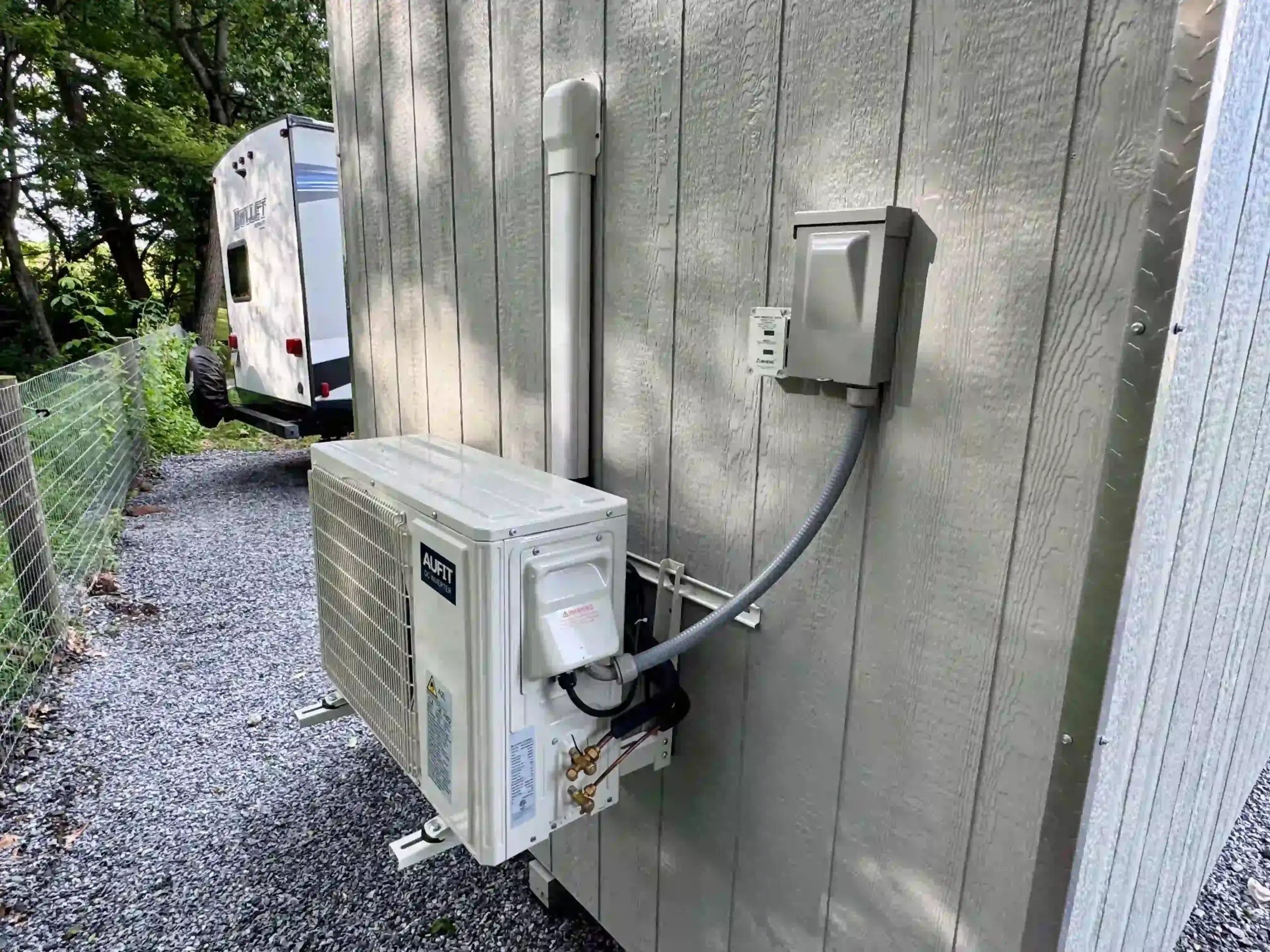 The exterior condenser and electrical hookup for a mini-split AC and heating system on a finished shed from Mill Run Storage.