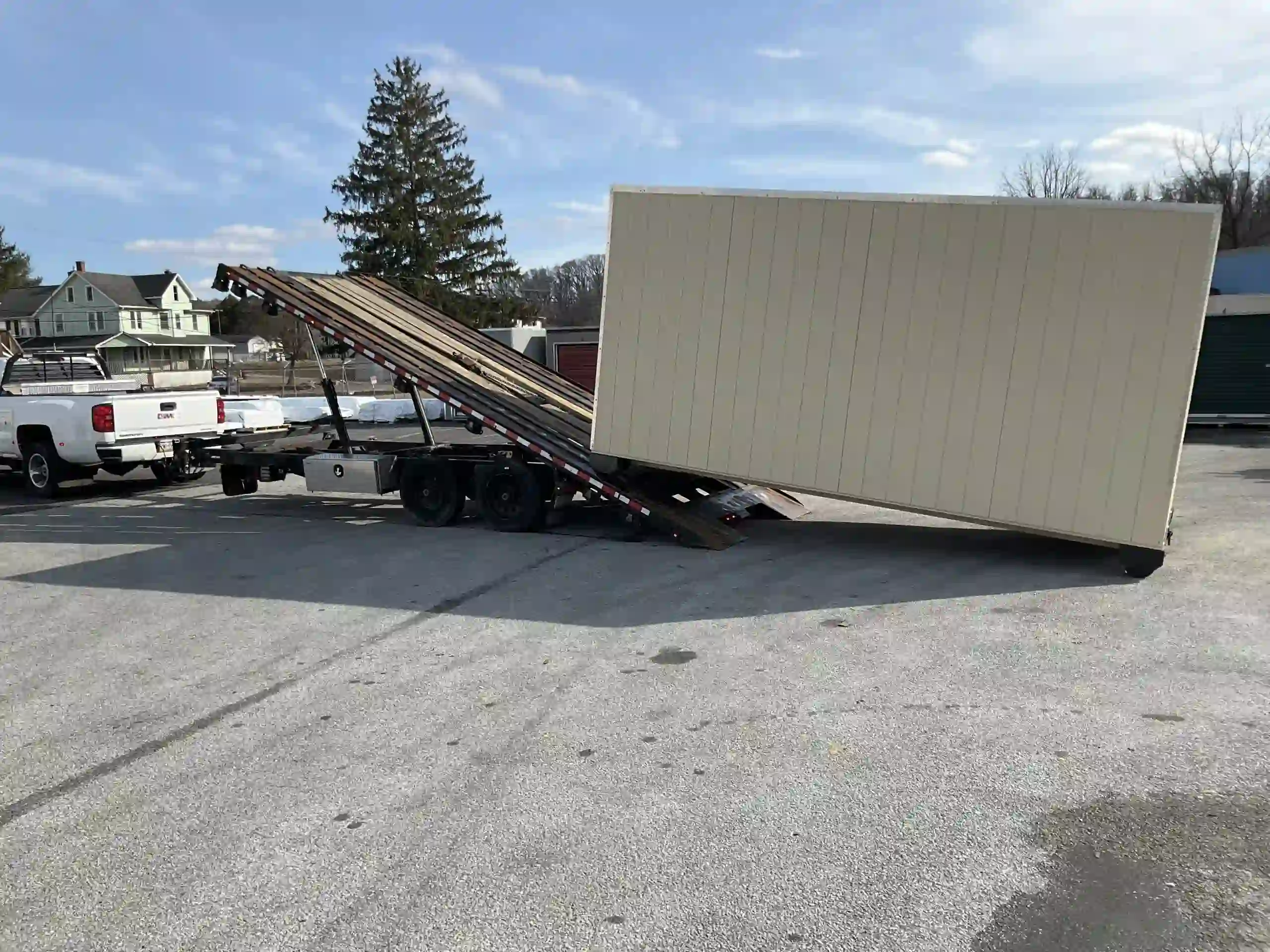 A large portable building being carefully unloaded from our specialized tilt-bed trailer at a customer's location.
