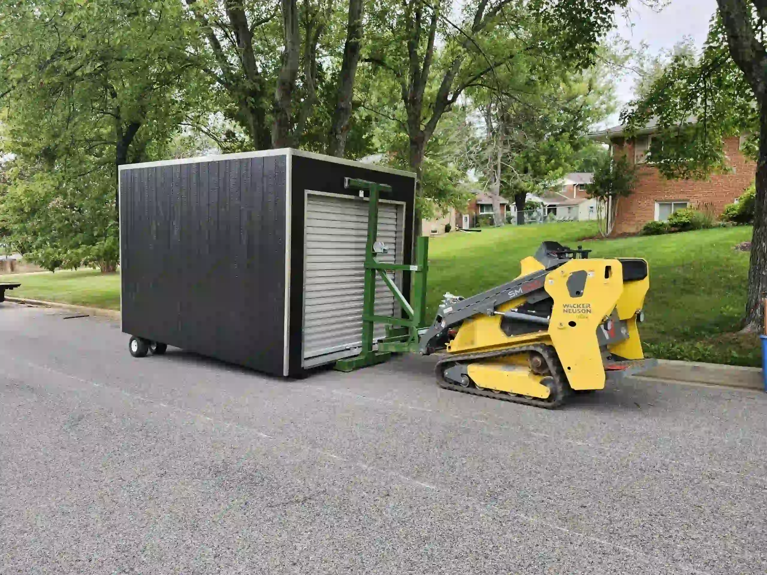 Our specialized tracked shed mover connected to a portable storage unit, ready for precise placement in a tight residential area.