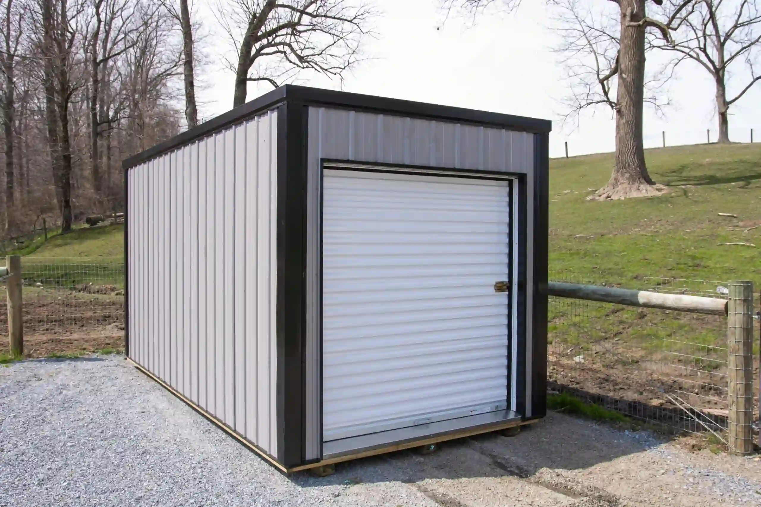 A modern metal portable storage shed with a roll-up door, installed on a gravel pad in Lancaster County by Mill Run Storage.