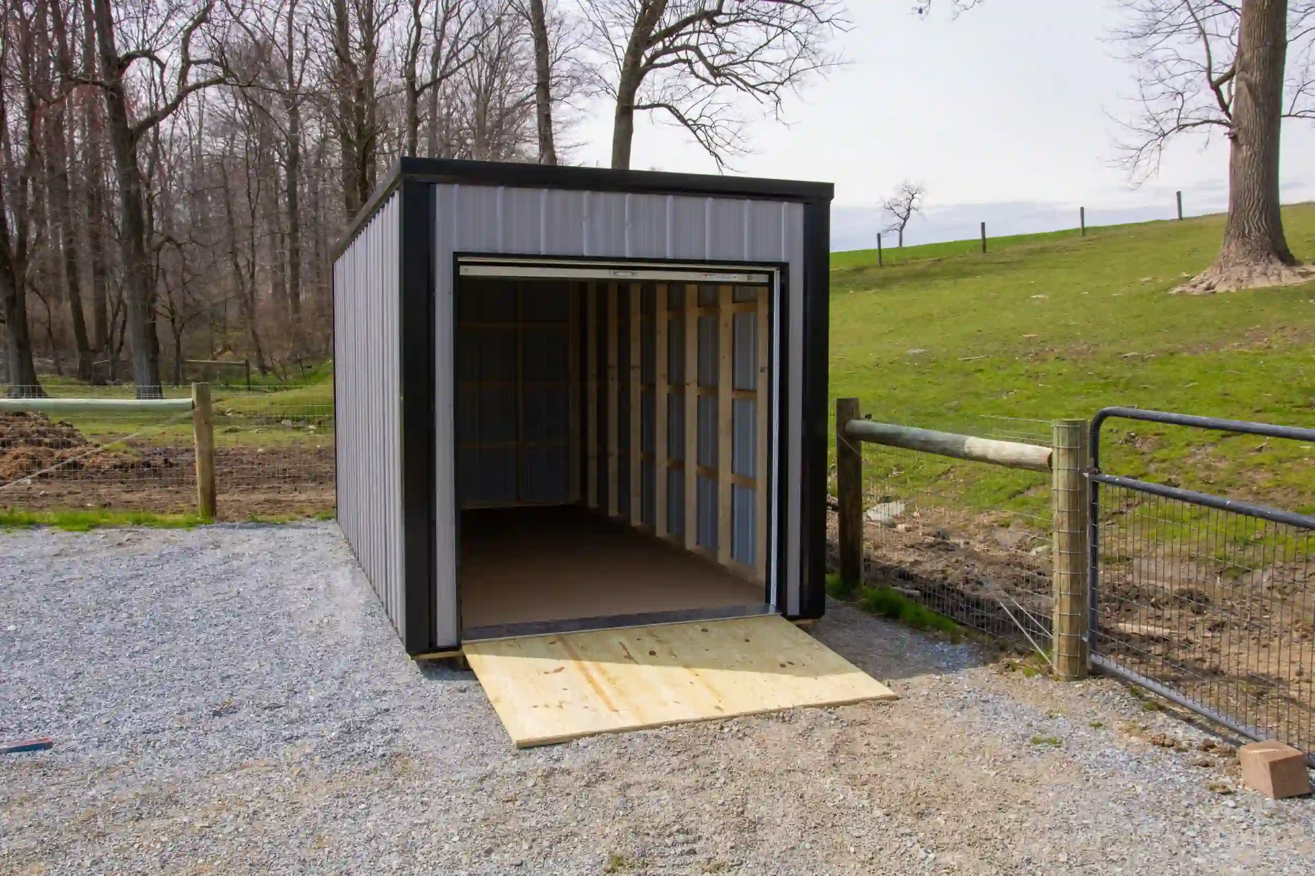 A Mill Run Storage portable container with a convenient wooden ramp, ready for easy loading and unloading in a backyard.