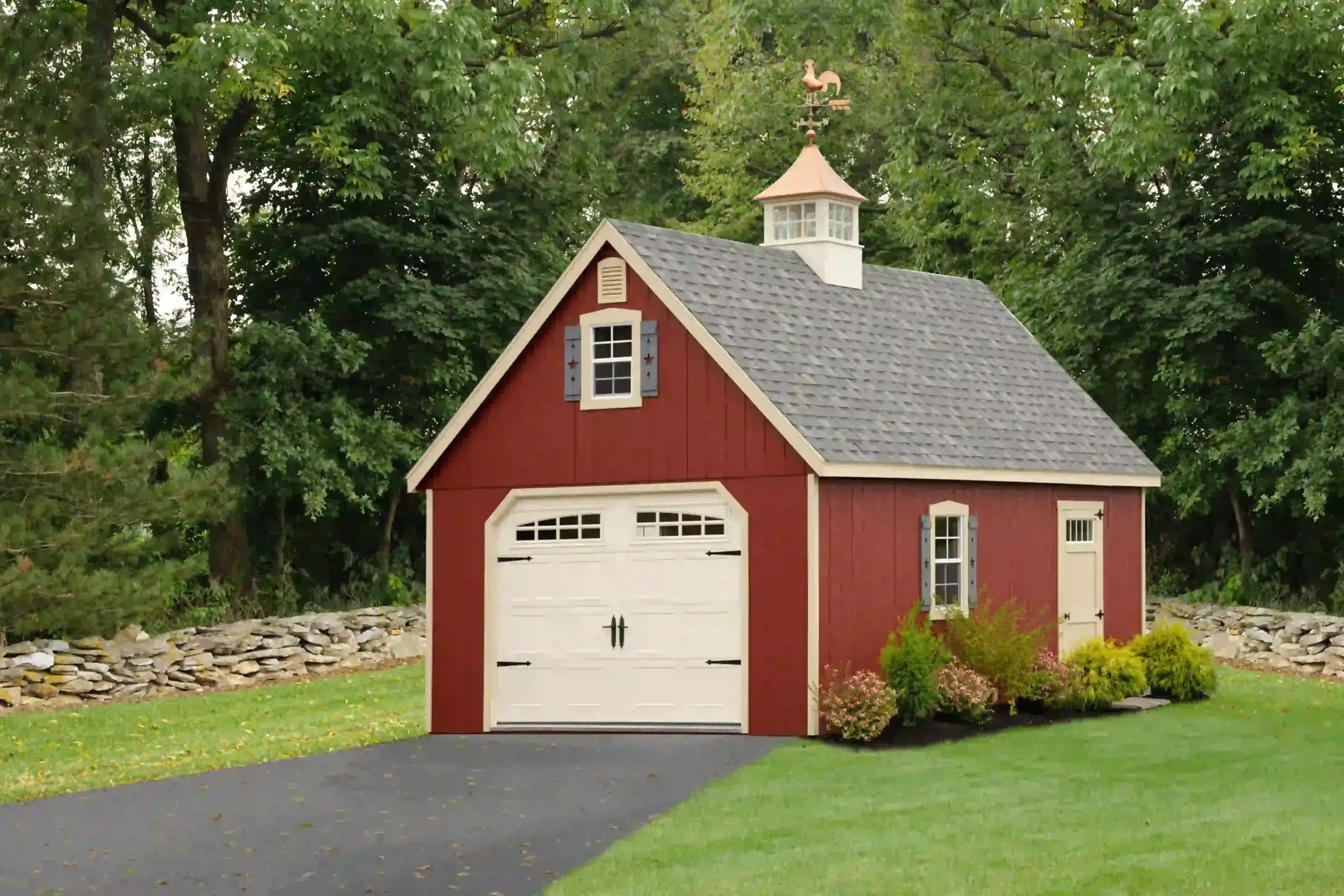 A beautiful red single-car garage featuring a carriage-style door, an attic dormer, and a copper weathervane cupola from Mill Run Storage.