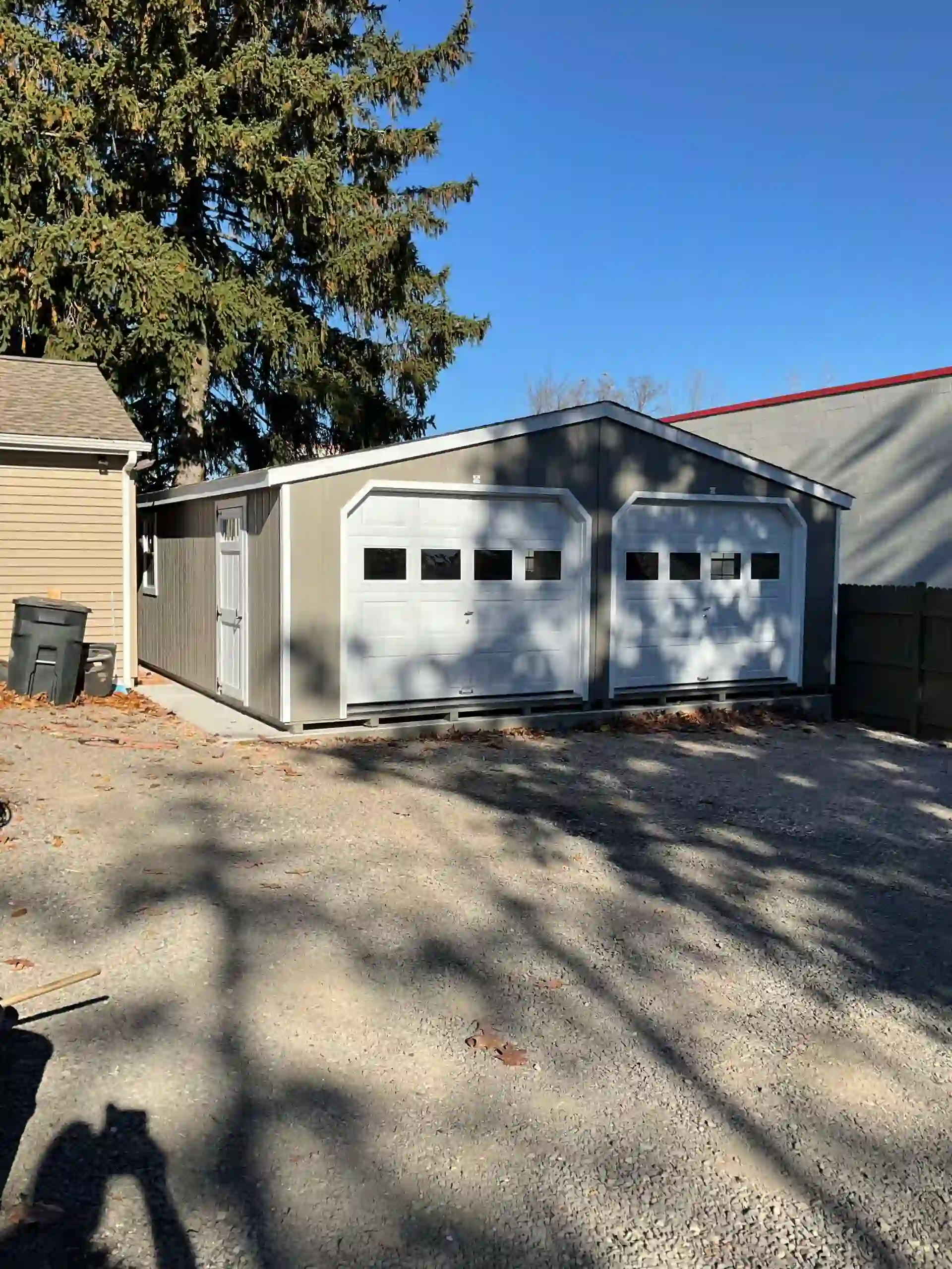 A handsome gray two-car detached garage with white carriage-style doors and a side entry, installed by Mill Run Storage in Lancaster, PA.