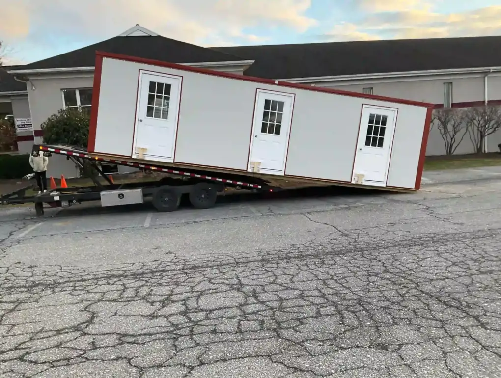 The process of unloading a large, three-door portable office building from our specialized delivery trailer.