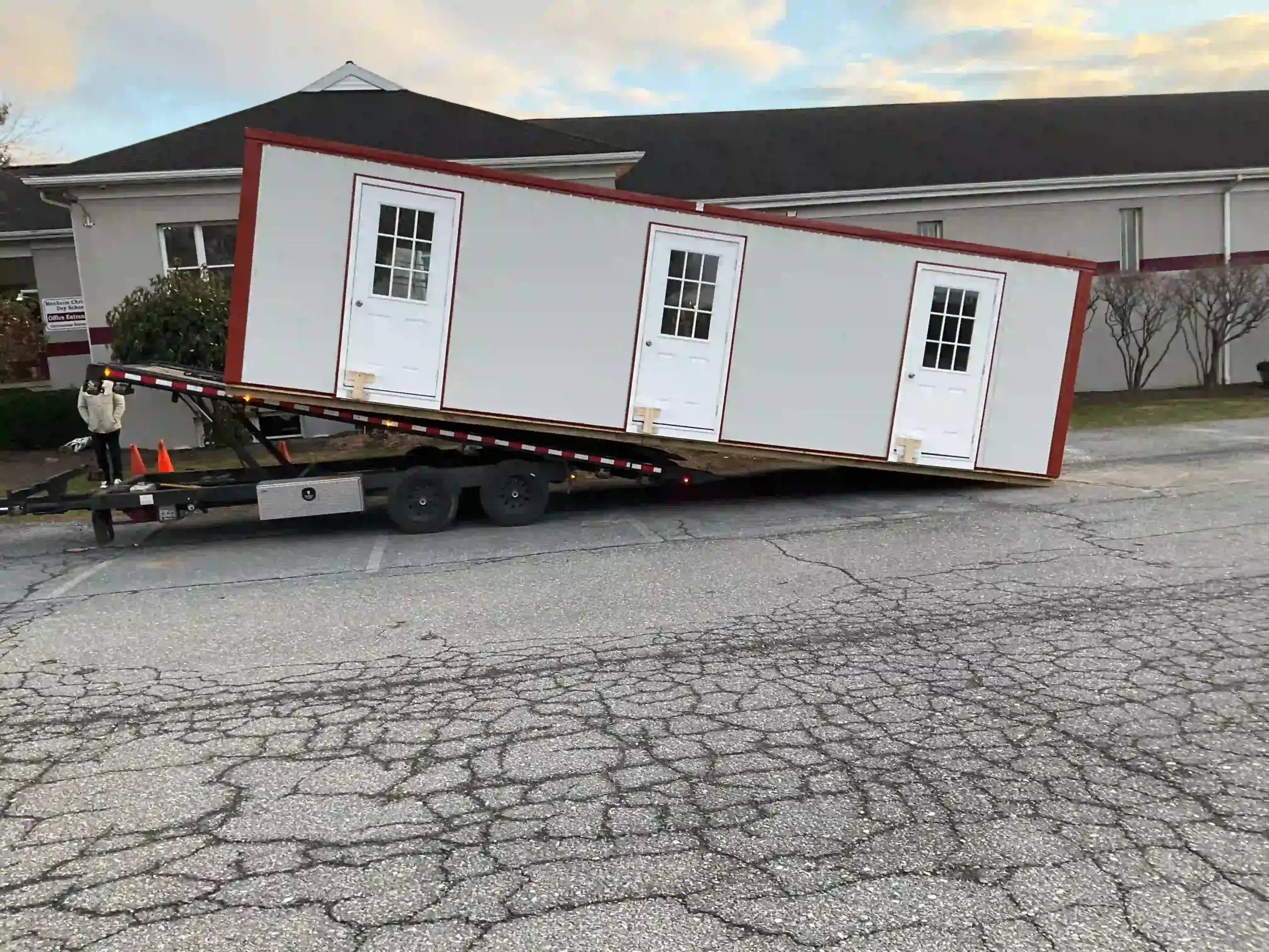 The process of unloading a large, three-door portable office building from our specialized delivery trailer.