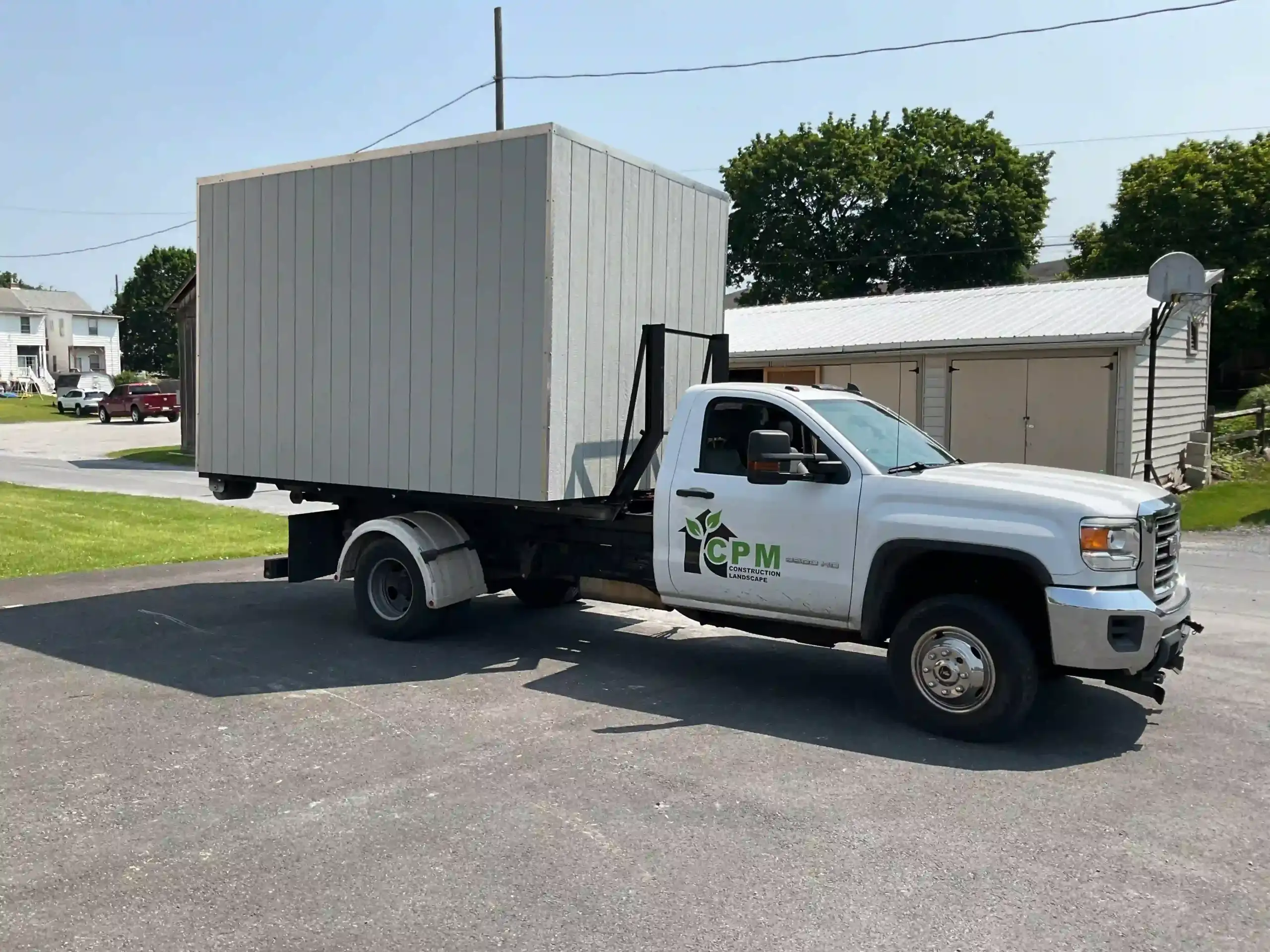 A new storage shed being delivered on a specialized truck, showcasing the delivery and installation service offered by Mill Run Storage.