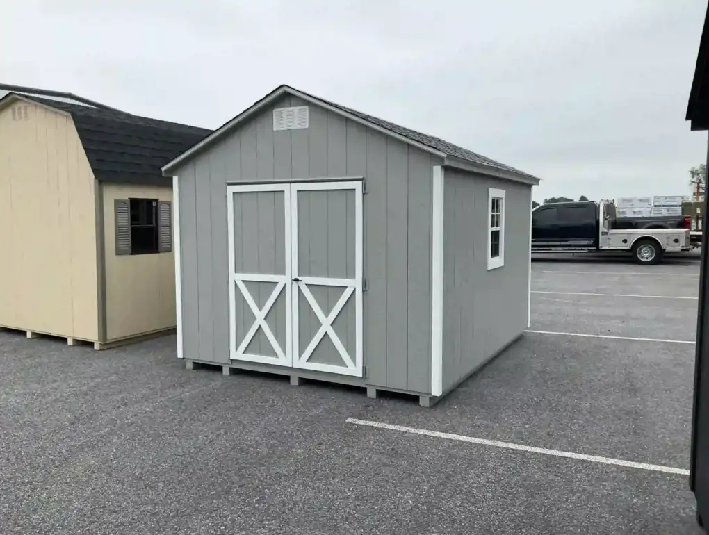 A gray A-frame garden shed featuring classic white crossbuck doors and a side window, available for sale at Mill Run Storage.