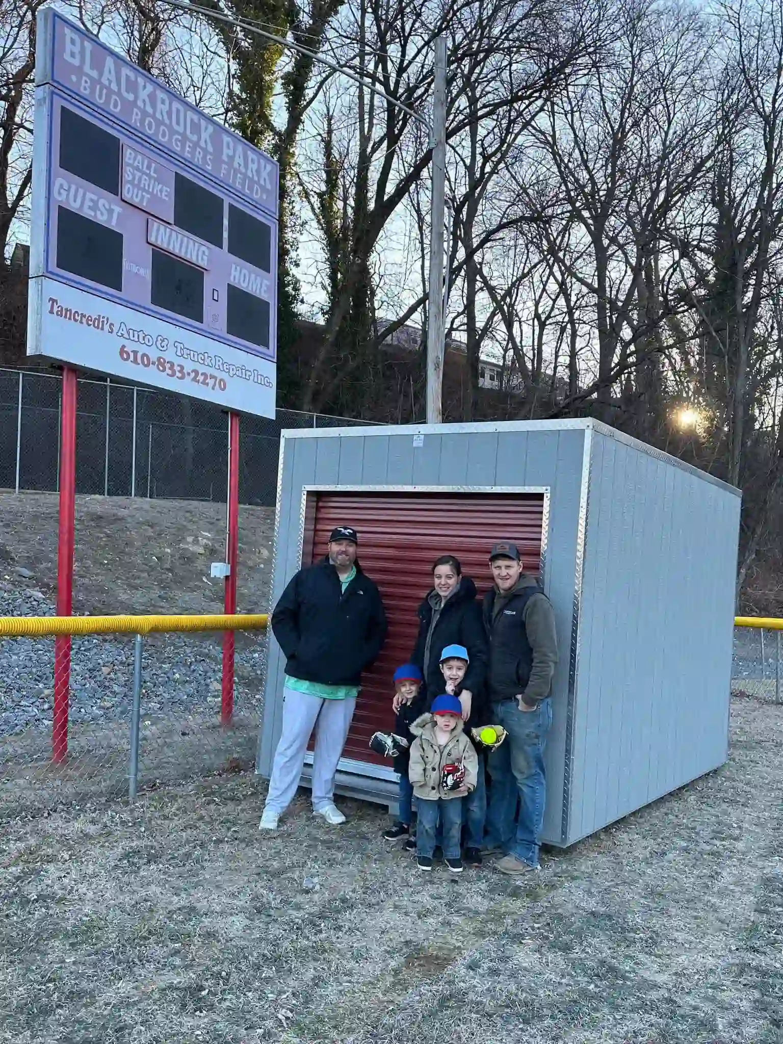 A happy family and community members with their new Mill Run Storage unit, used for storing baseball equipment at Blackrock Park.