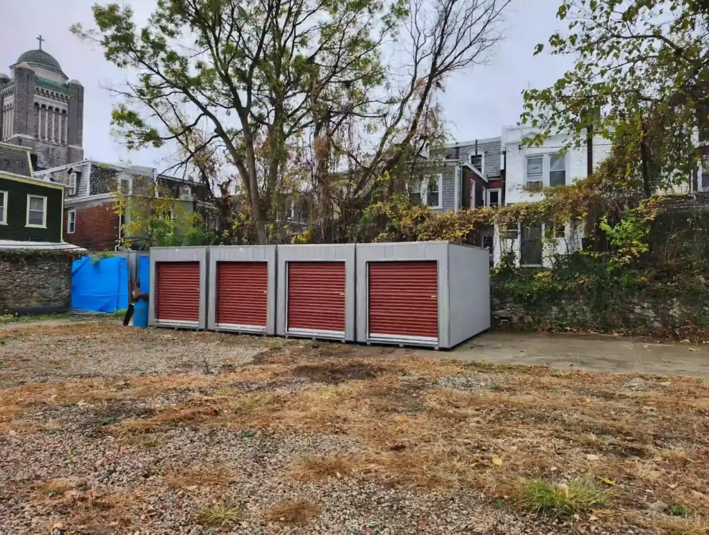 A row of four durable, portable storage units with red doors, providing a secure commercial storage solution from Mill Run Storage.