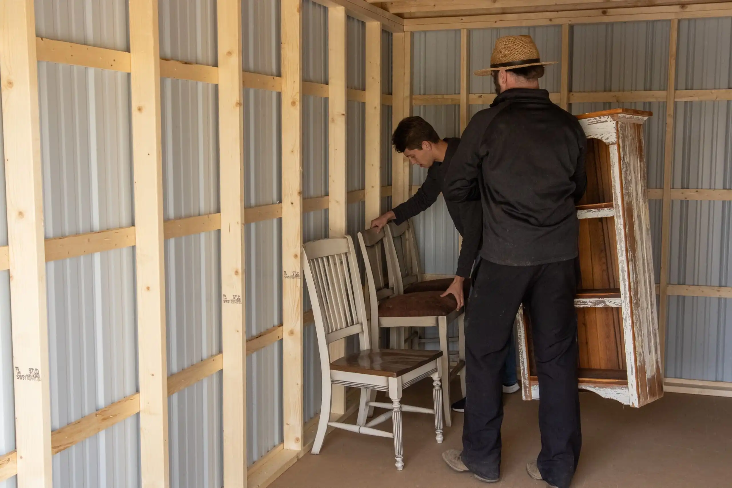 Two men carefully moving furniture into a spacious Mill Run Storage unit, perfect for moving or temporary storage.