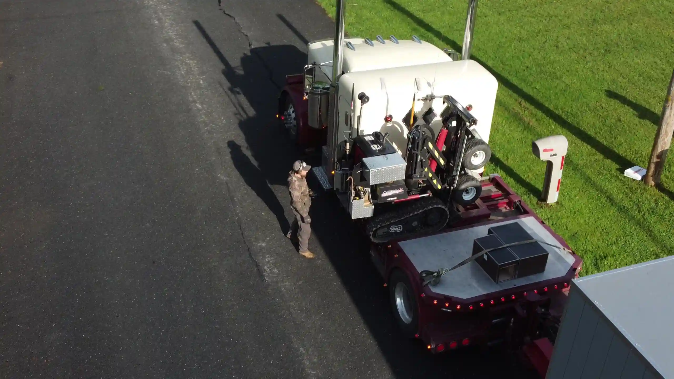 Our delivery expert unloading the specialized tracked shed mover from the semi-truck, preparing for on-site placement.